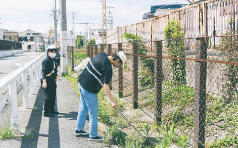 総合就労支援福祉施設・にしなりWingの利用者さんが津守駅に面した道路に落ちているごみを拾う様子